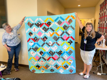 Seabeck, Sharing - Penny S helps Kristina L show her completed quilt top